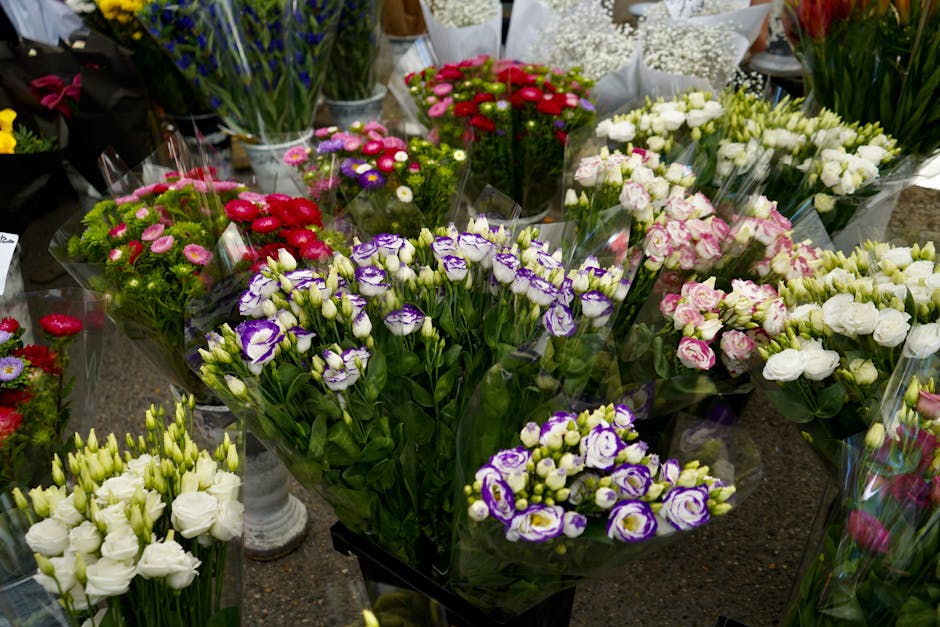 A variety of freshly cut floral arrangements featuring primarily white and purple flowers, including lisianthus with ruffled petals, delicate pink and white roses, and small daisy-like blooms in shade